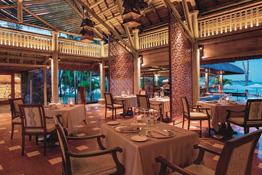 Gedecktes Restaurant im offenen Stil mit elegantem Interieur, Holzelementen und Blick auf den Strand.