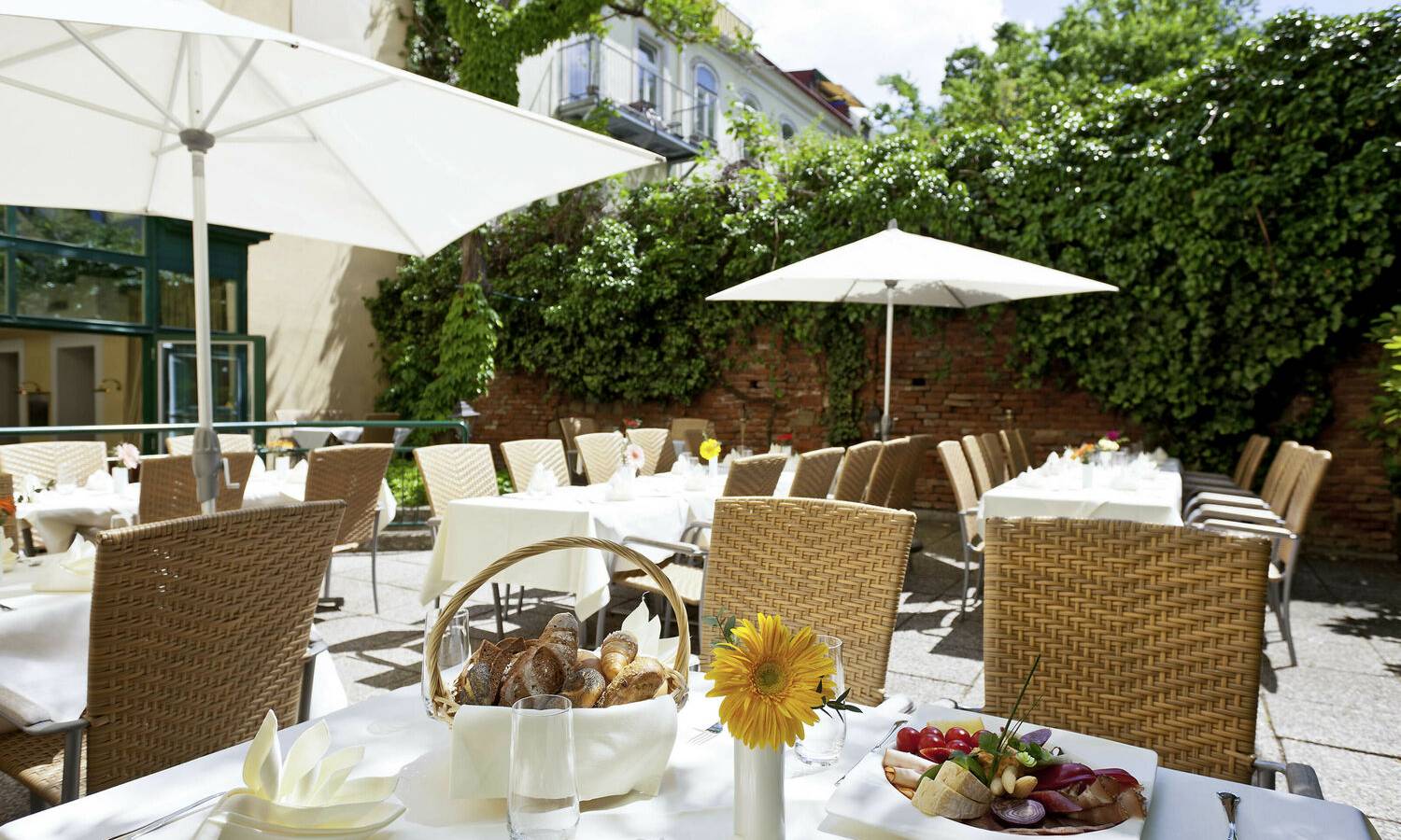 Gastgarten des Mercure Grand Hotel Biedermeier Wien mit Sitzplätzen in begrünter Innenhof-Atmosphäre