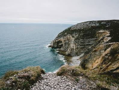 Felsküste an der Pointe du Raz in der Bretagne, mit einem Pfad im Vordergrund und weitem Blick auf den Atlantik.