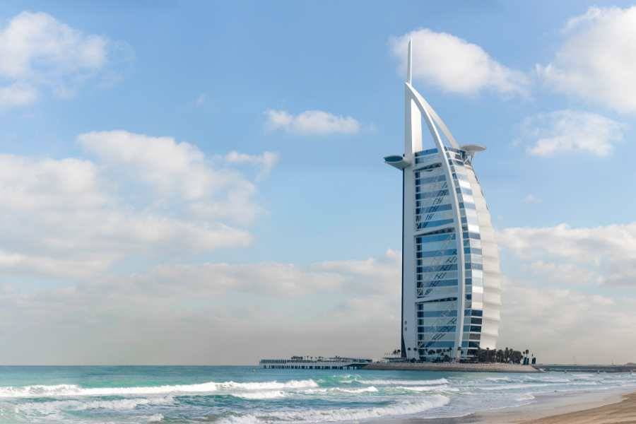 Das Burj Al Arab, ein ikonisches segelförmiges Hotel am Meer mit Wolkenhimmel im Hintergrund.