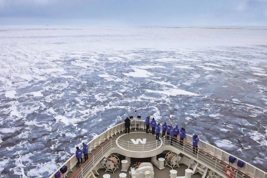 Blick vom Schiff auf vereiste Ostsee mit Passagieren an Deck