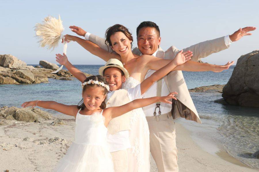 Die vierköpfige Familie lacht in die Kamera und hält die Arme als Pose in die Luft.