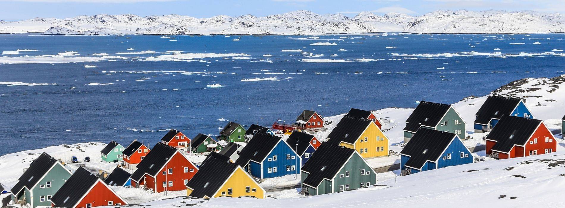 Bunte Häuser in Grönland im Schnee am Wasser