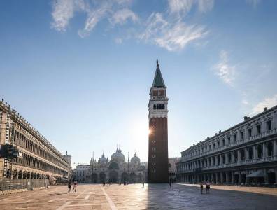 Weitwinkelaufnahme des Markusplatzes in Venedig mit dem Campanile und der Basilika im frühen Tageslicht.