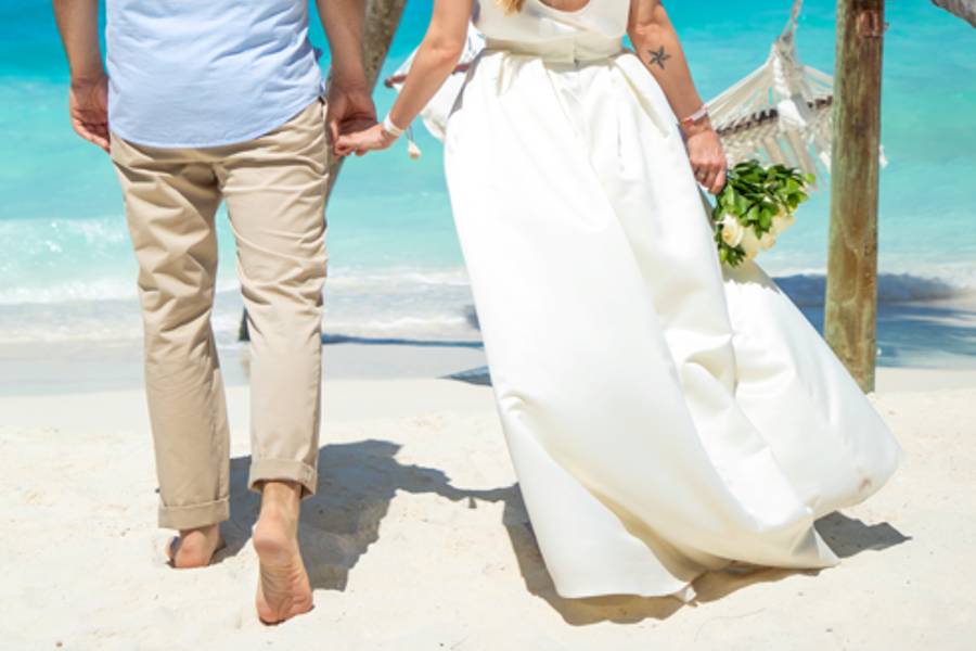 Das Hochzeitspaar von hinten mit Ausblick auf einen strahlend blauen Himmel.