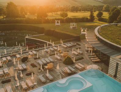 Weitläufige Sonnenterrasse und Poollandschaft des Reiters Supreme Hotels mit Blick auf die umliegende Natur im Abendlicht.