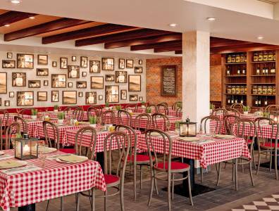 Italienisches Restaurant an Bord der AIDACosma mit rot-weiß karierten Tischdecken und stimmungsvoller Beleuchtung