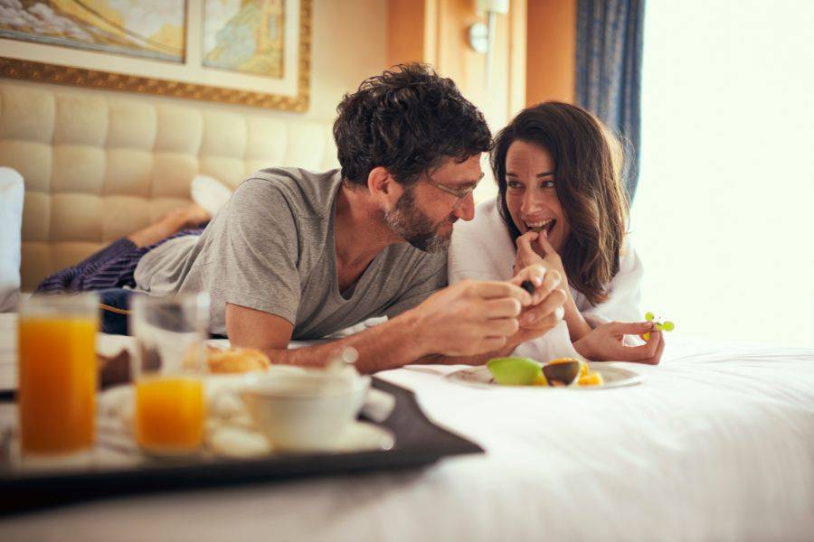 Paar genießt Frühstück im Bett während einer luxuriösen Cunard Kreuzfahrt