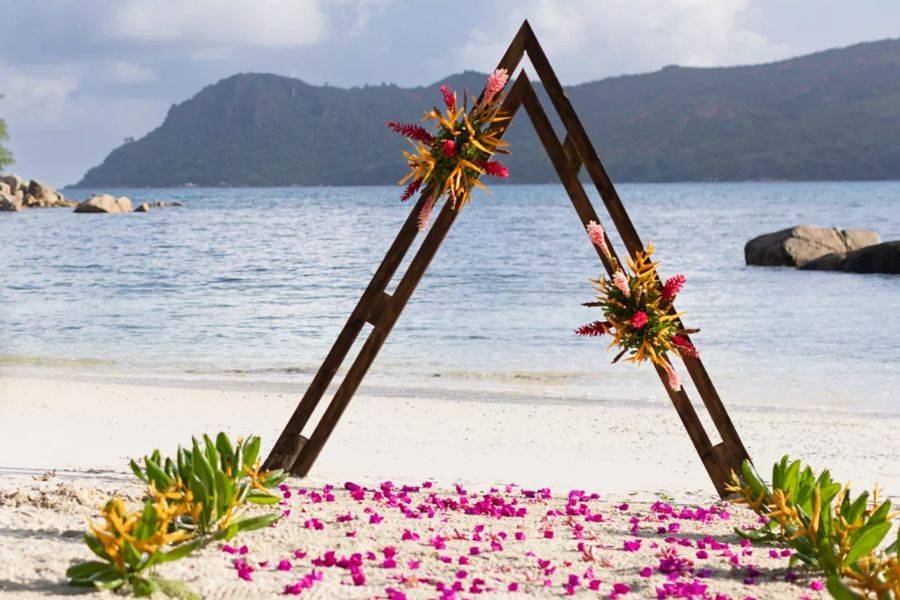 Tropisch dekorierter Traubogen für eine Strandhochzeit im Raffles Praslin Resort auf den Seychellen – exklusive Hochzeitslocation direkt am Indischen Ozean.