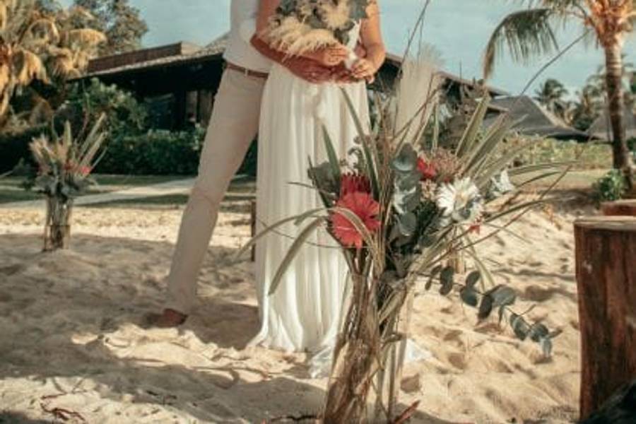 Man sieht das Brautpaar von vorne, der Bräutigam umarmt die Braut von hinten und beide lachen in die Kamera.