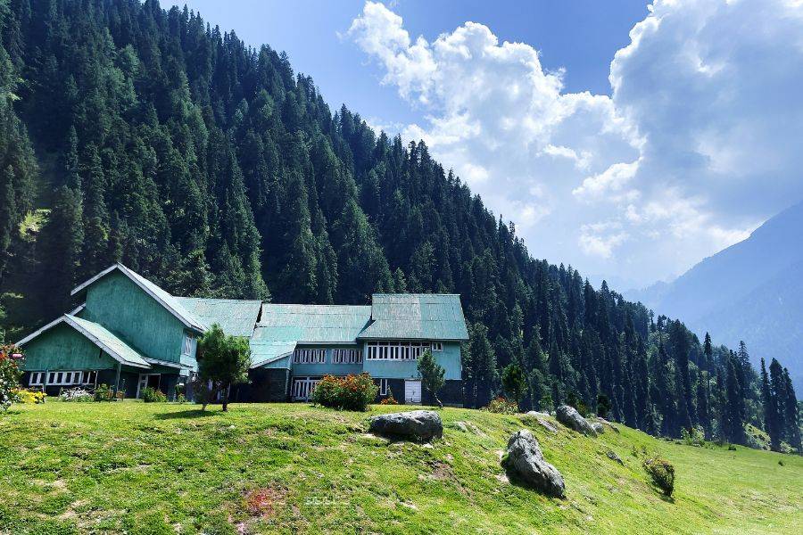 Traditionelles Ferienhaus in den Bergen, umgeben von Wiesen und dichtem Wald