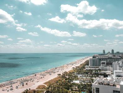 Panoramablick auf Miami Beach mit Skyline, Art-Déco-Hotels und langem Sandstrand – typisches Bild für einen Badeurlaub in Südflorida.